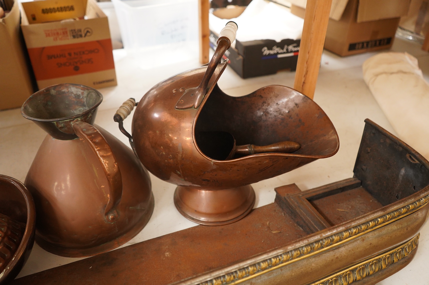A collection of metalware to include a steel and brass fender, a helmet scuttle, 19th century jelly mould and a harvest jug